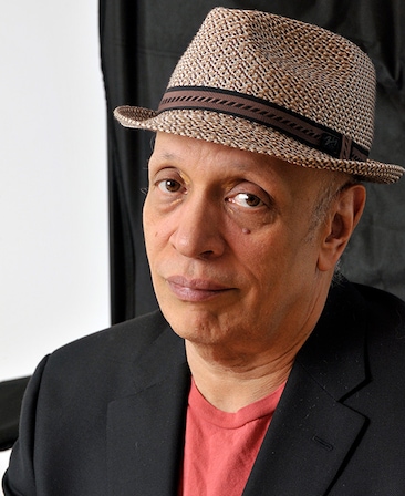 Walter Mosley Headshot wearing an orange shirt and patterned hat