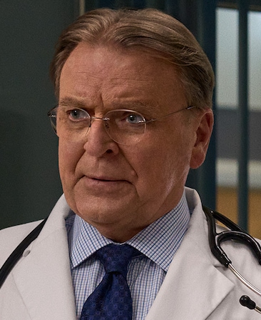 Headshot of David Rasche playing Dr. Pankowitz wearing a white doctors coat and a stethoscope around his shoulders.