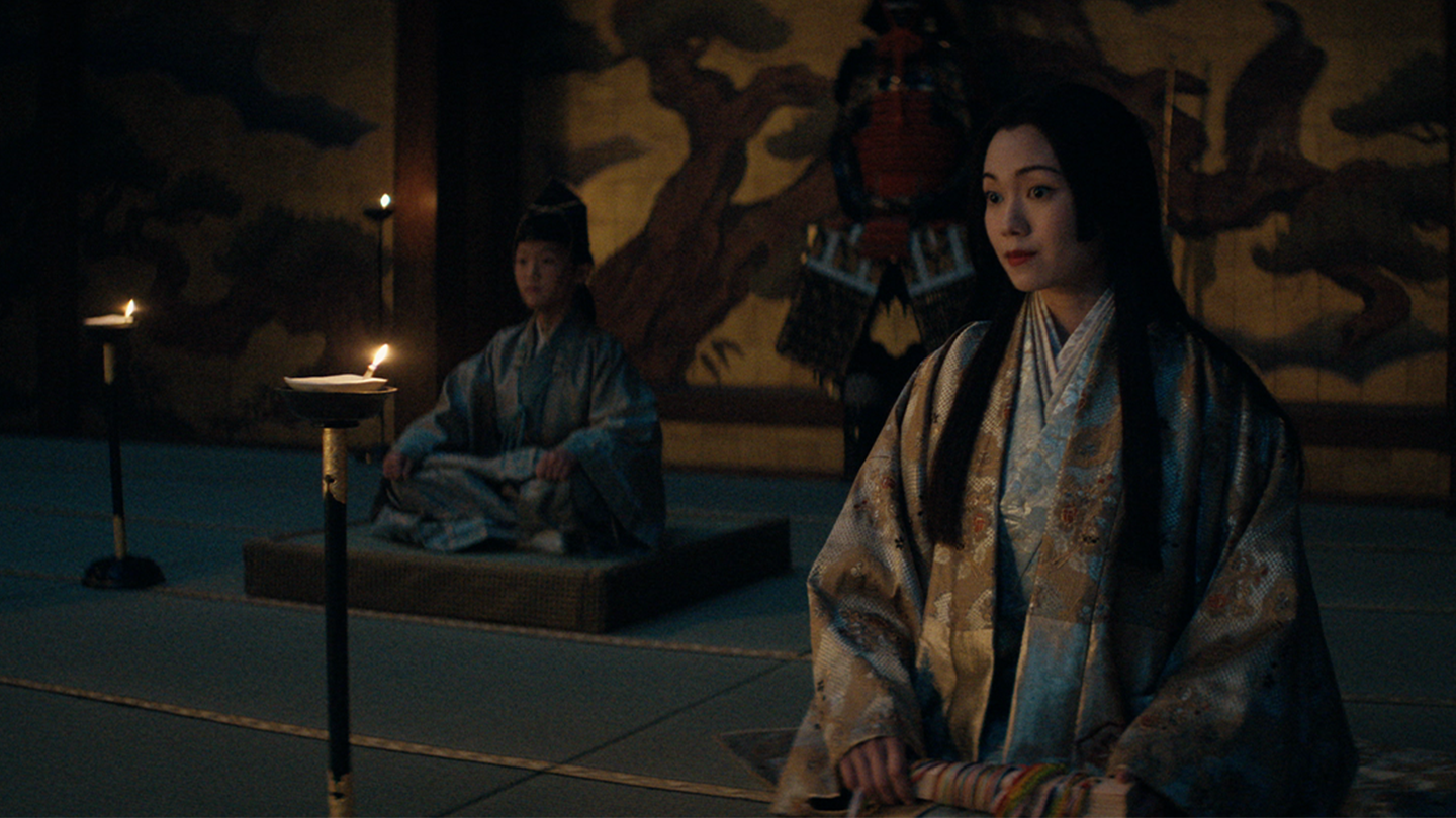 Ochiba and Yaechiyo sit in the Osaka meeting hall with the Taiko's armor in the background