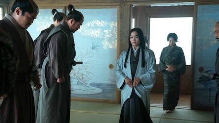 Mariko standing in front of a line of samurai. 