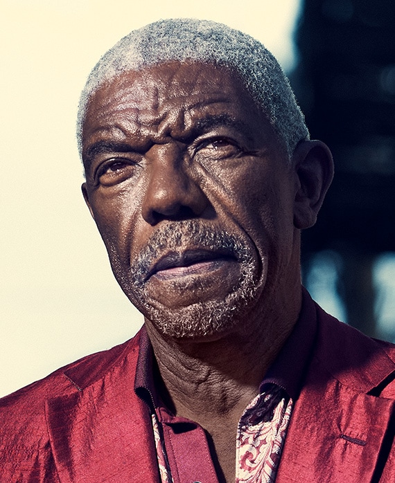 Vondie Curtis Hall headshot wearing a red shirt and standing outside