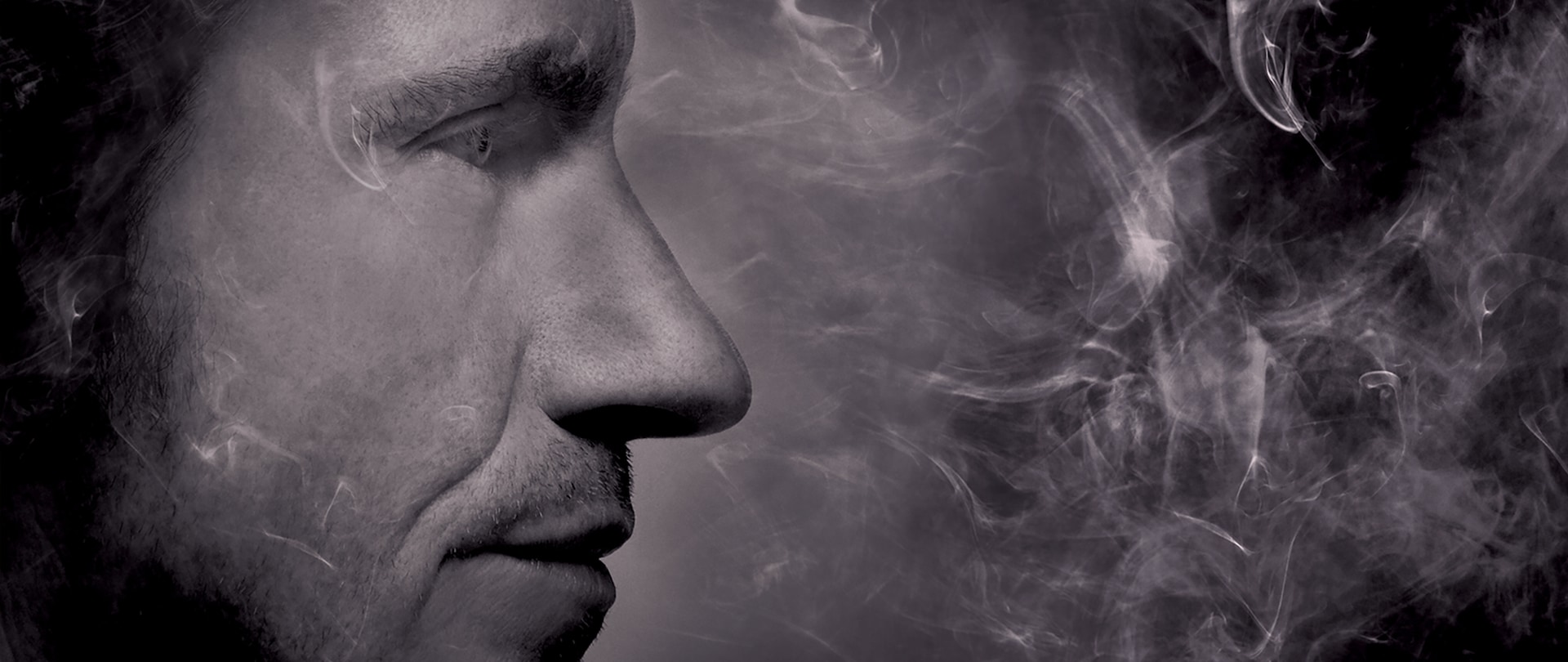 Grayscale close-up side profile of Denis Leary with smoke plumes surrounding his face for FX's Rescue Me