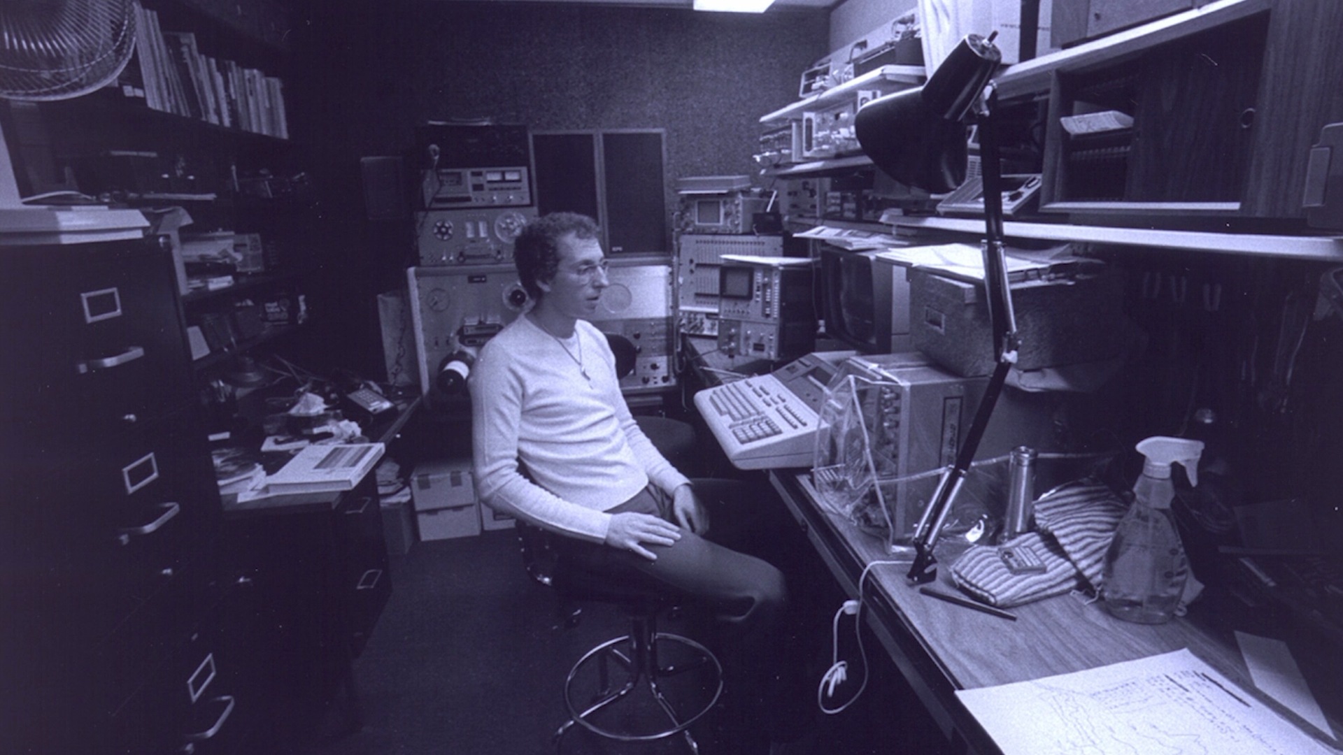Man sitting in a room with a bunch of old technical equipment