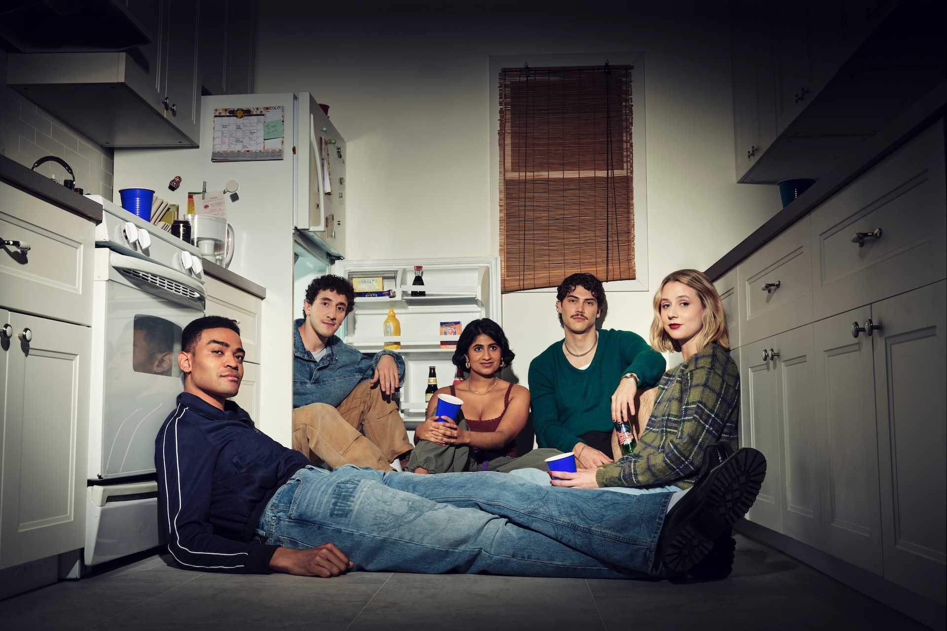 Cast of FX's Adults sitting on the floor of a kitchen. 