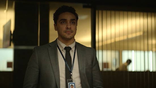 Man in a suit wearing a badge in a office