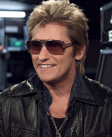 Denis Leary headshot wearing a chain necklace, sunglasses and leather jacket