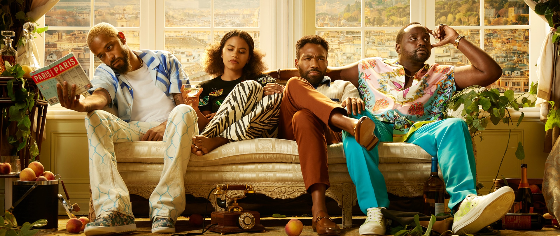 Cast of FX's Atlanta sitting on a light elegant couch with peaches on the ground.