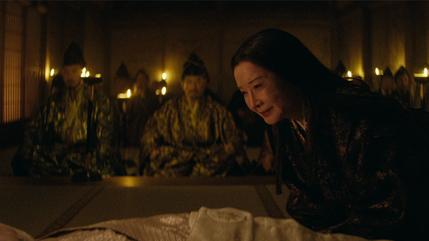 The Taiko on his death bed with Daiyoin crying at his side as seated warlords watch.