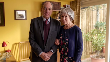 Jackie standing next to Jim with her arm wrapped around his. 