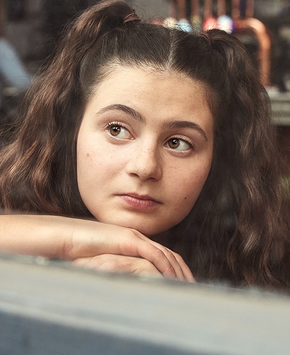 Zoe Athena headshot wearing pig tails in her hair and resting her chin on her hands