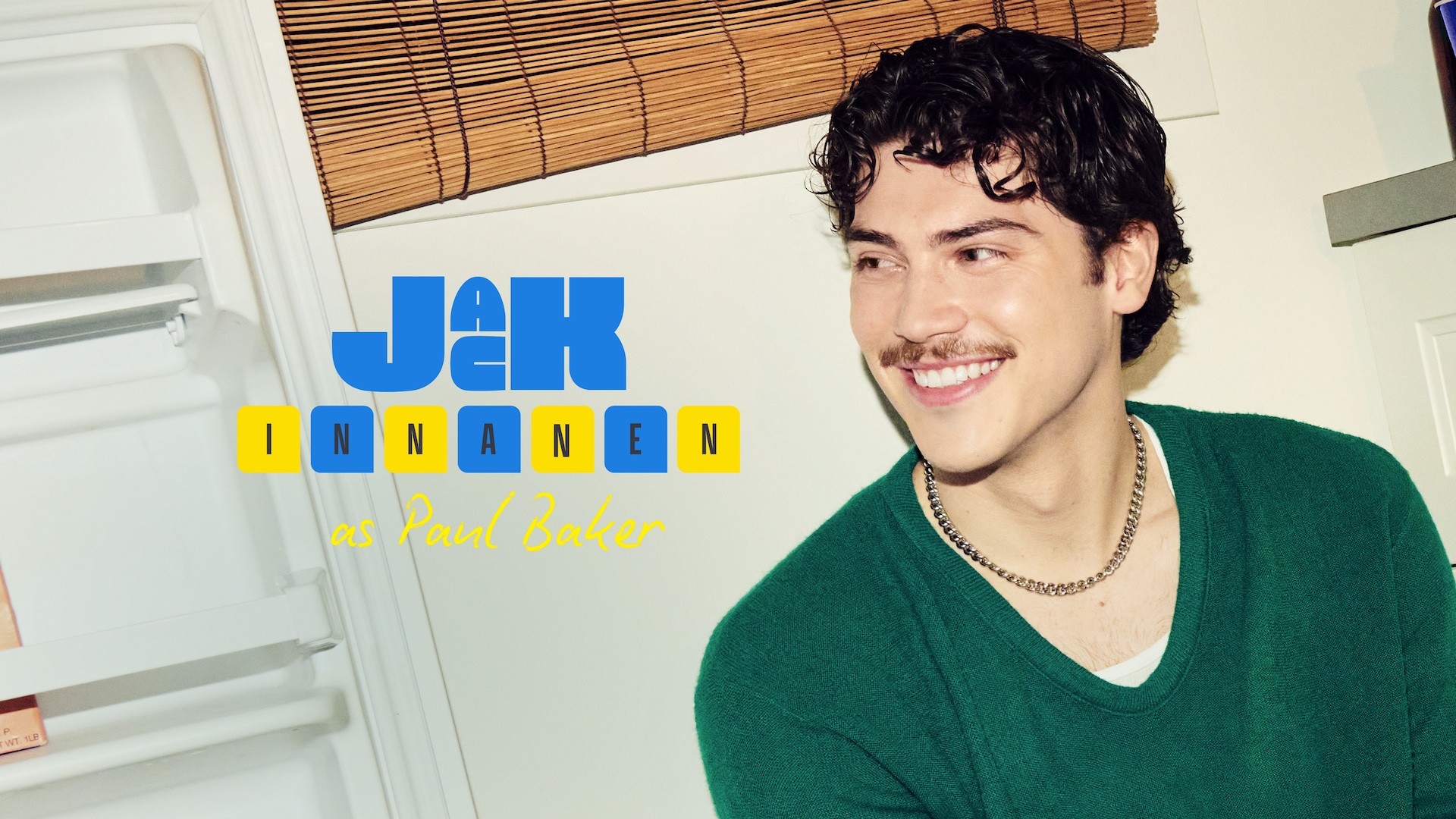 Jack Innanen as Paul Baker in FX's Adults, wearing a green sweater and gold necklace, smiling towards an open fridge.