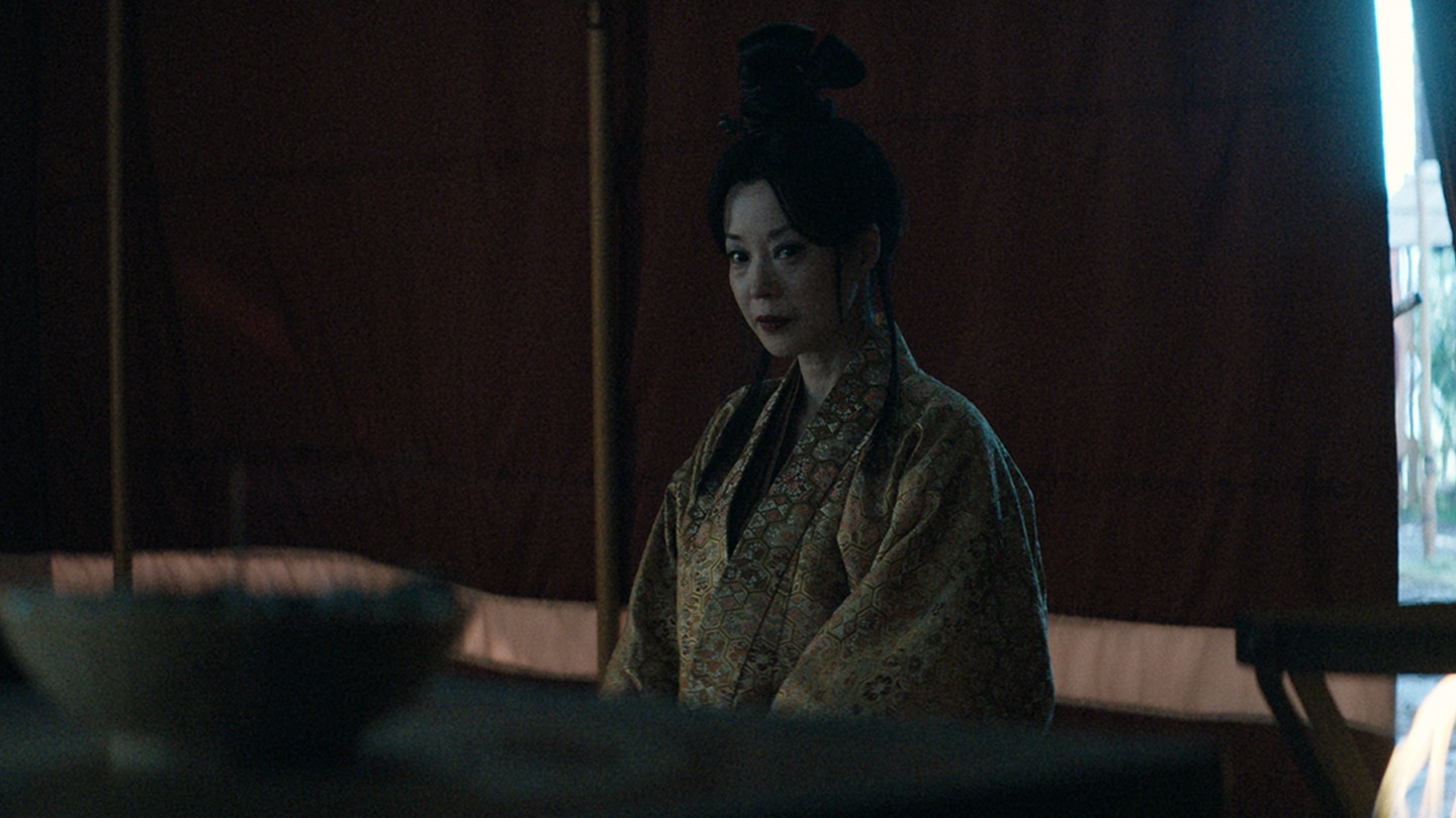 Gin dressed in yellow attire staring at a stick of incense