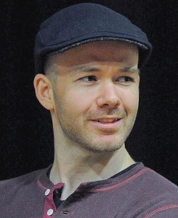 Headshot of Michael Lennox wearing a burgundy shirt and a black hat.