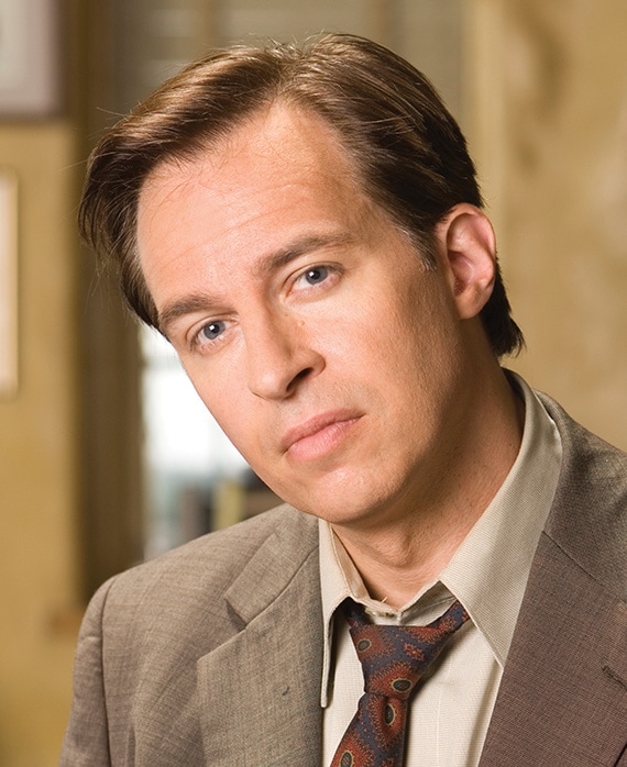 Jay Karnes headshot wearing a white shirt with red tie and a beige jacket 
