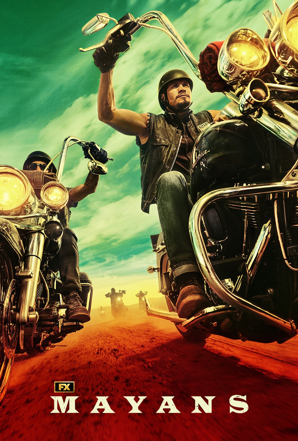 JD Pardo riding a motorcycle outside on red dirt and green sky in the background for Mayans MC
