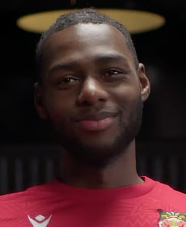 Arthur Okonkwo headshot in a red WAFC tshirt in a dimly lit room.