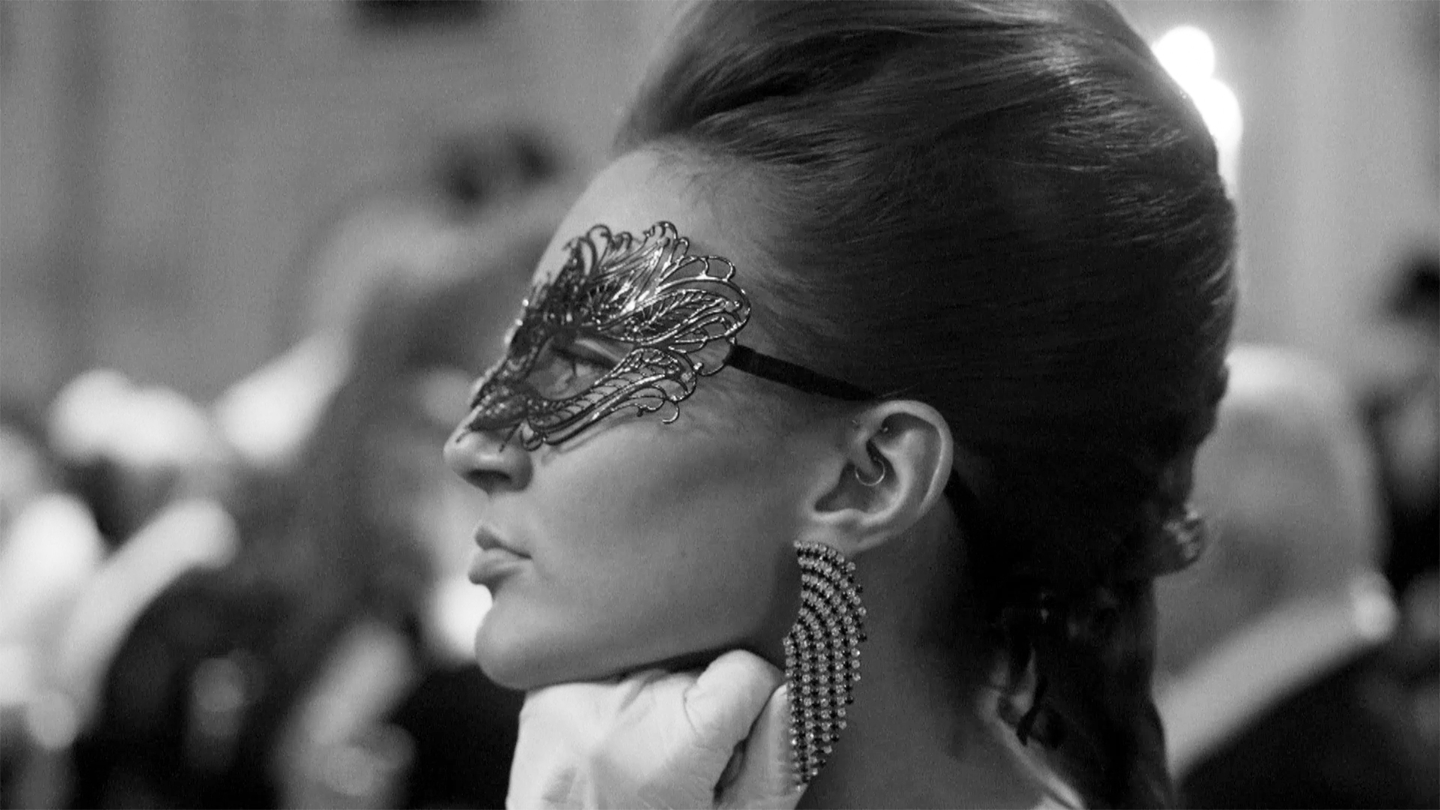 Black and white profile view of a woman with a masquerade mask on.