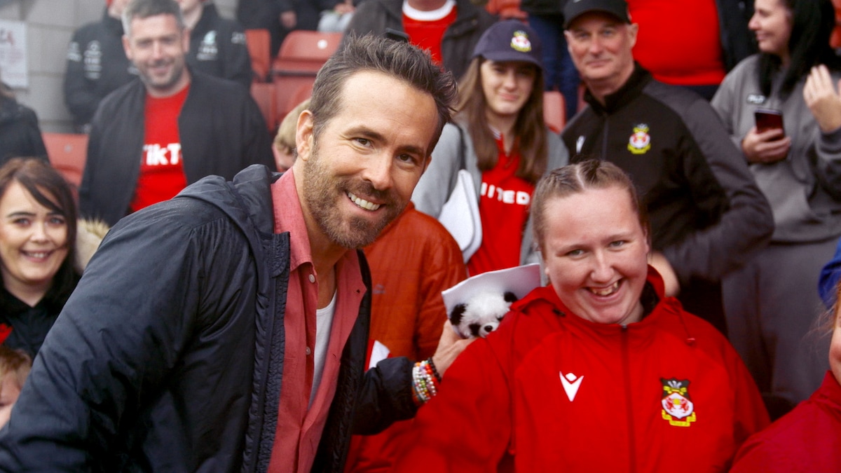 Ryan Reynolds smiling next to a Wrexham fan