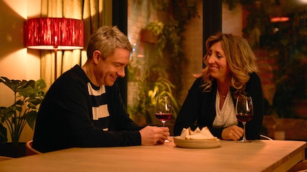 Paul and Ally sitting at the dining table smiling with wine in hand. 