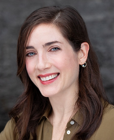 Caroline Moore headshot wearing an earring and a khaki shirt with buttons 