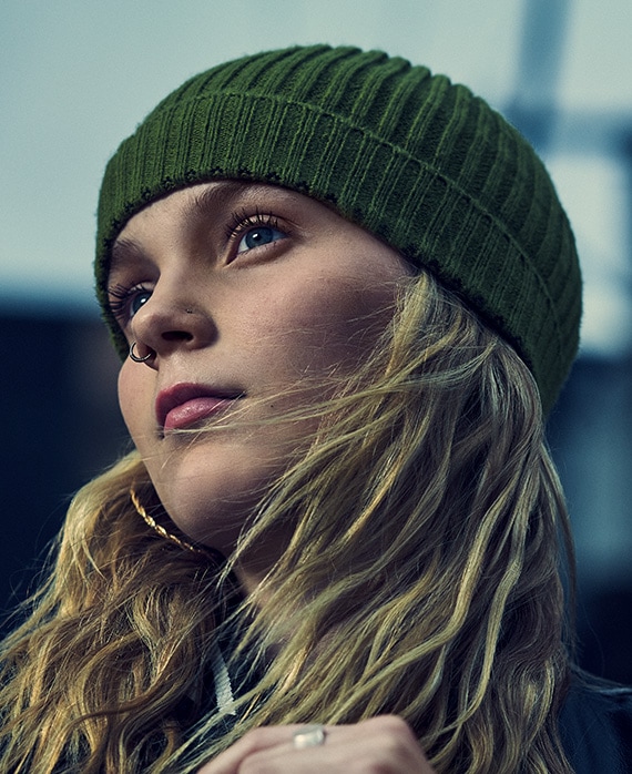 Vivian Olyphant headshot wearing a green beanie and earrings