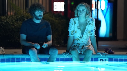 Dave and Ally sitting outside on the floor with their legs in a pool