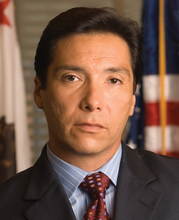 Benito Martinez headshot wearing a blue shirt with red tie and a black jacket