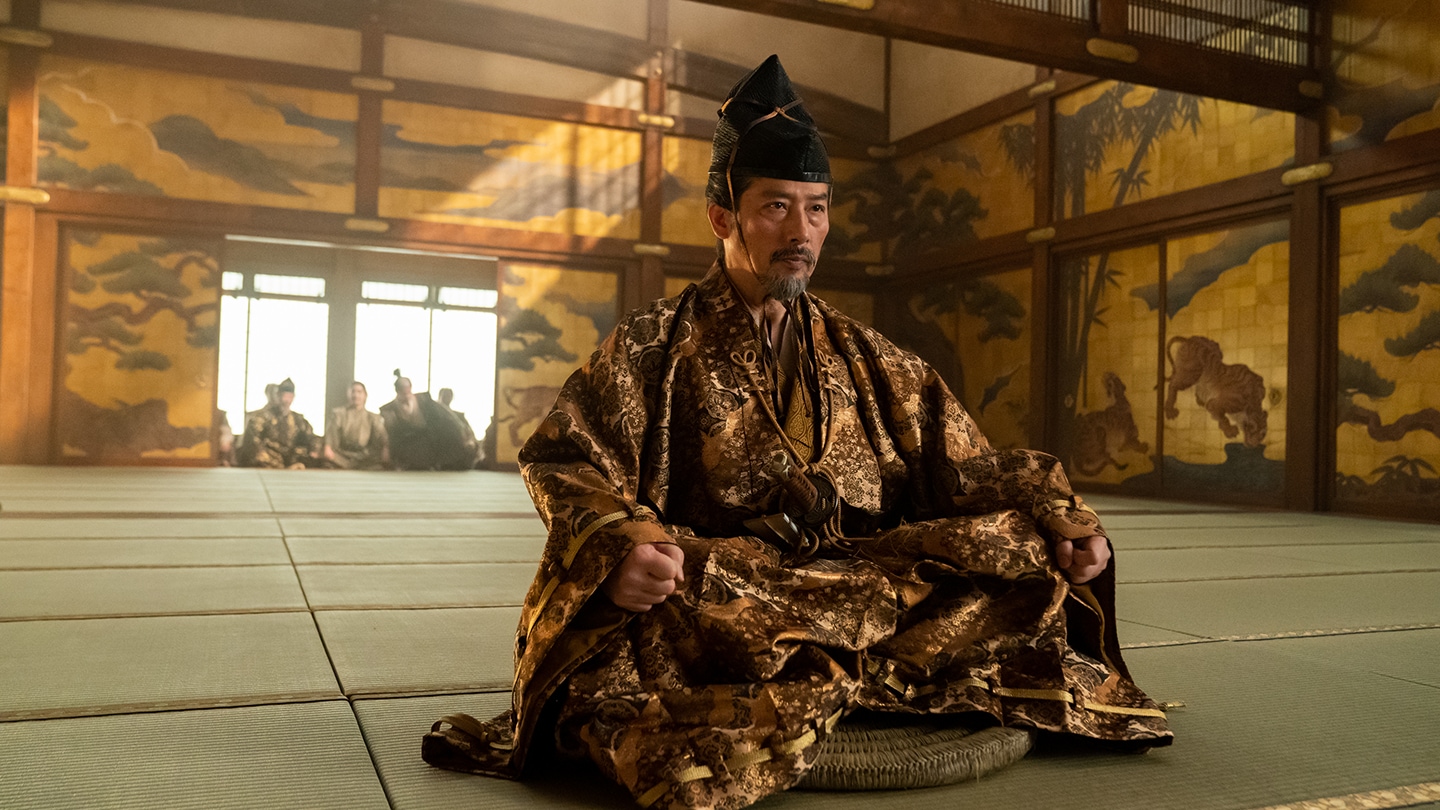 Close up of Lord Yoshii Toranaga sitting in the center of the Osaka Castle meeting room