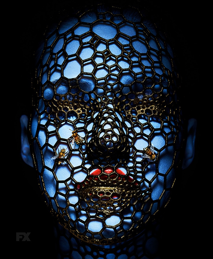 Blue woman with red lipstick covered in honeycomb pattern net and bees from FX's AHS Cult