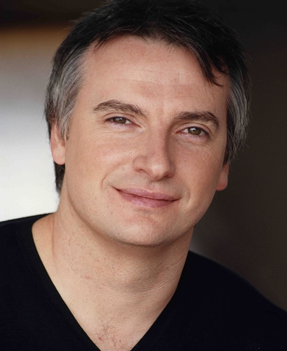 Glen Mazzara headshot wearing a black shirt with a v cut neckline