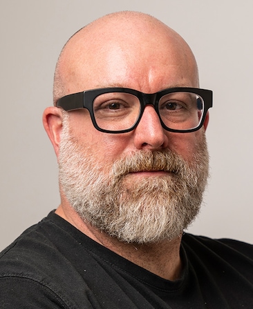 Lee Mason wearing black glasses and a black shirt