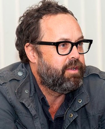 Headshot of Scott Robertson, Executive Producer of FX's Grotesquerie, in grey jacket and black glasses.