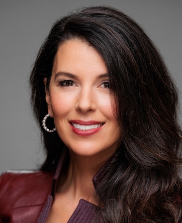 Linda Pizzuti Henry headshot in a burgundy jacket with hoop earrings.
