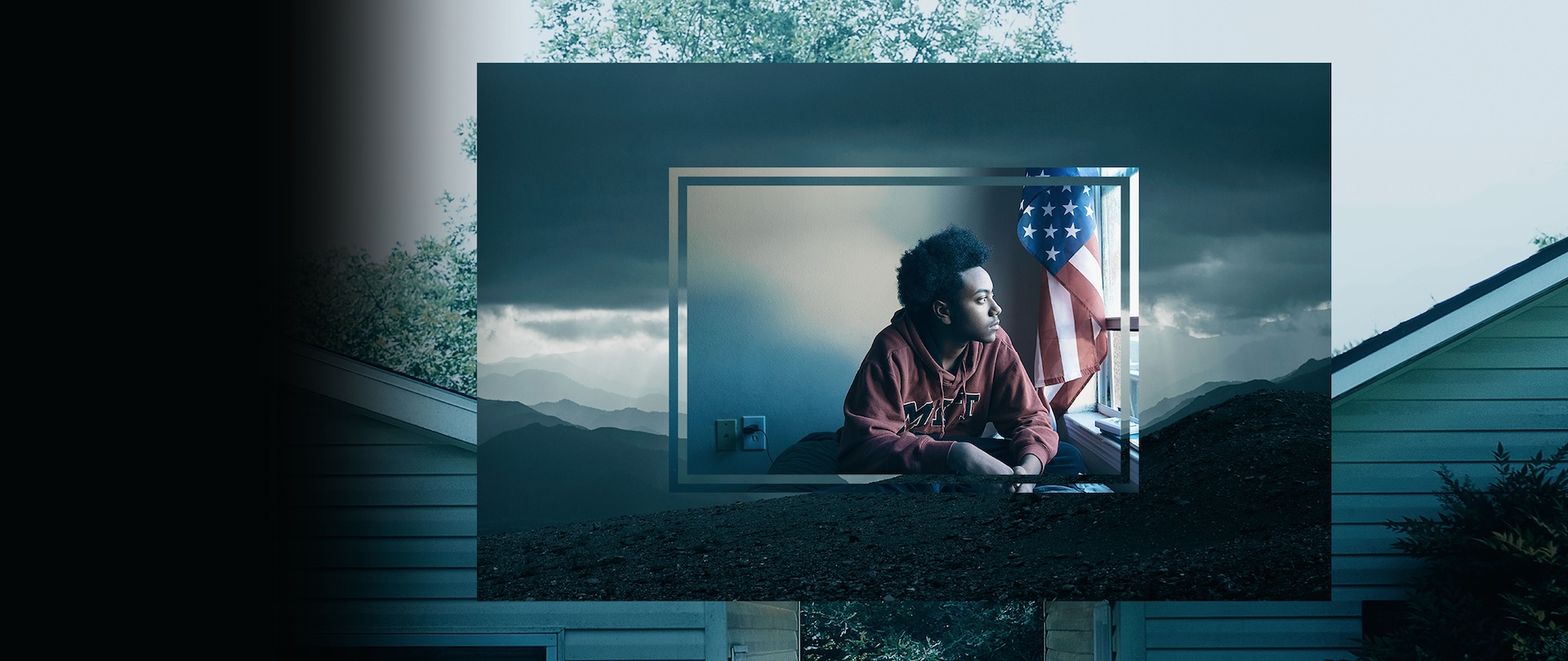 Young man in an MIT sweatshirt sitting by a window with an American flag behind him for FX's documentary series The Weekly