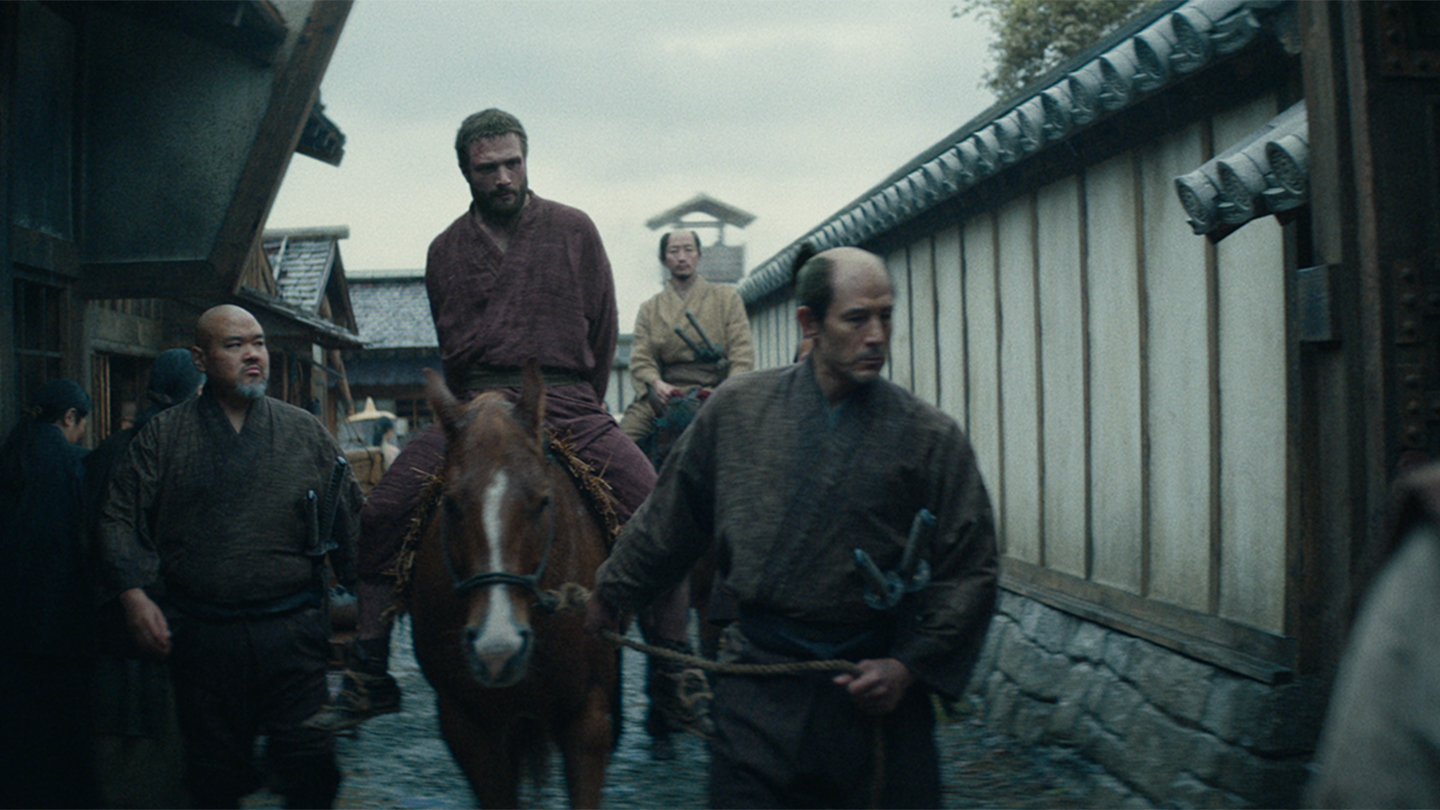A captive Blackthorne on horseback being led through Osaka by guards