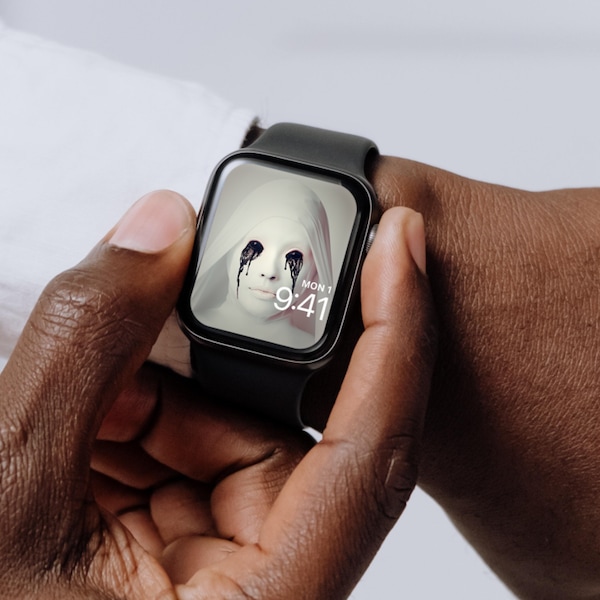 Man wearing Apple Watch with lock screen of completely white nun with black eyes crying black tears from FX's AHS Asylum