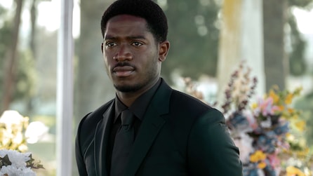 Franklin wearing a black suit and tie with flowers in the background