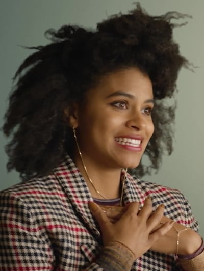 Van from Atlanta FX show wearing black and red plaid blazer smiling with hands on chest