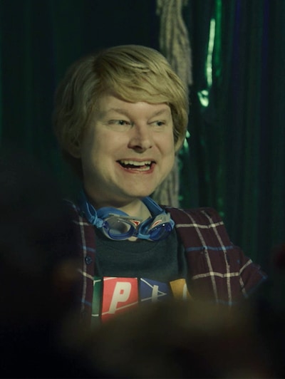 Colin with blonde long hair and goggles around his neck