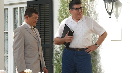 Alfred Molina as Robert Bob Aldrich holding black book next to man in grey suit standing outside in Feud FX show 