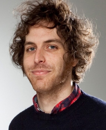 Headshot of executive producer Jonathan Krisel, wearing a red plaid shirt with a deep blue sweater over it.