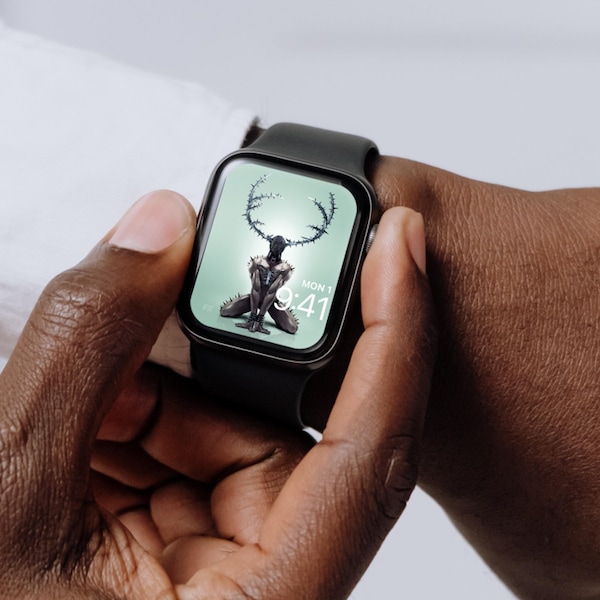 Man wearing Apple Watch with lock screen of muscular man on hands and knees wearing black mask and antlers from FX'S AHS NYC