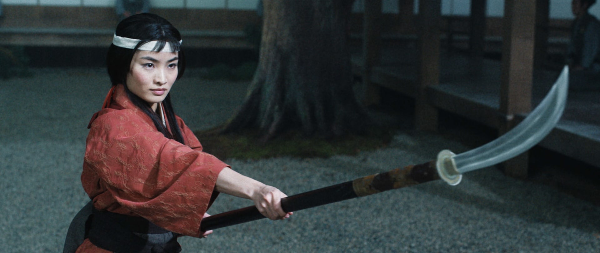 Mariko holding a Naginata spear training in a courtyard