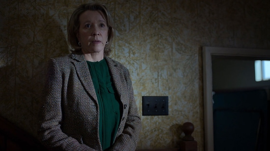 Woman leaning against a wall with yellow wallpaper in the dark