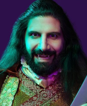 Kayvan Novak headshot with fangs like teeth and wearing a sequence style top