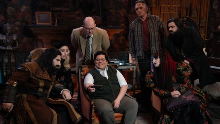 Cast of What We Do in the Shadows looking at a phone. 