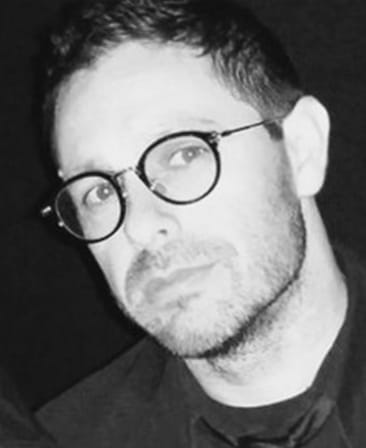 Eric Amadio headshot wearing black glasses in a black and white effect