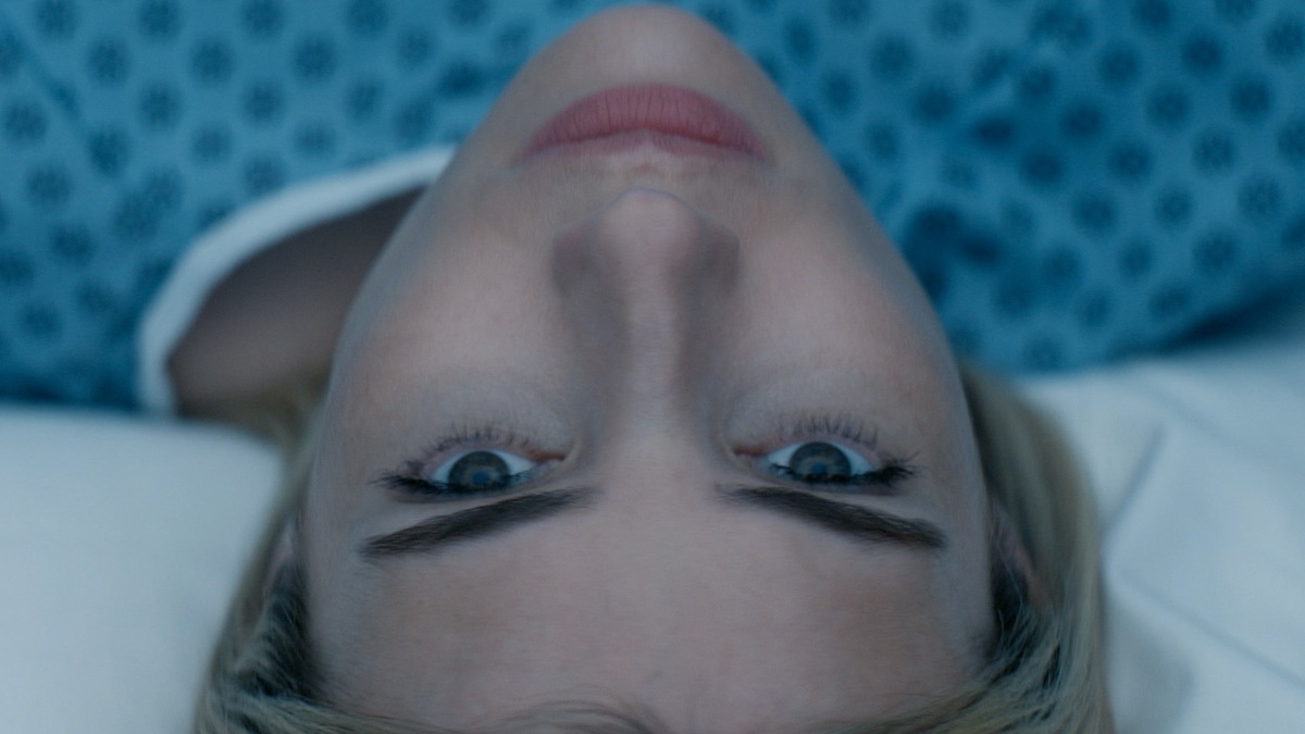 A women laying down on a white bed wearing a hospital gown.