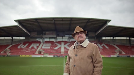 Man in a brown hat and jacket standing on the Wrexham soccer field