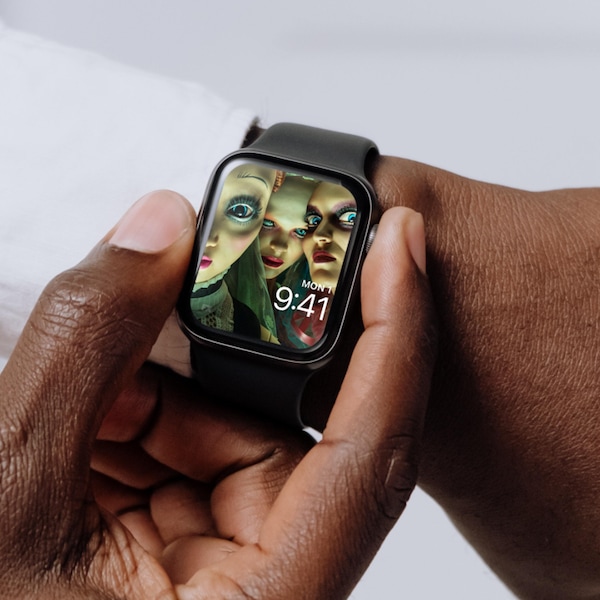 Man wearing Apple Watch with lock screen of wide-eyed dolls and colorful clothes and makeup from FX's American Horror Stories